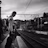 grayscale photo of man in white long sleeve shirt and black pants walking on train rail